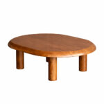 A luxury Dio teak wood coffee table with an oval design and thick cylindrical legs in a natural honey finish