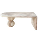 Side view of a modern oval coffee table made of light-colored Suar wood, featuring two stacked sphere legs and a waterfall edge