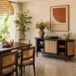 A professional lifestyle setting of the Nala curved teak sideboard in dark walnut finish, styled in a warm dining room with mid-century modern chairs and decor