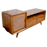 Angled perspective of Sora Split Level Teak Credenza featuring handcrafted teak wood construction, woven rattan cabinet door, open display shelf, and dual drawers with rounded edges.