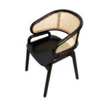 A high-angle, three-quarter view looking down on the Nara Teak Rattan Wave Chair with a black frame. The shot provides a clear view of the smooth black wooden seat and the entire curved inner surface of the cane backrest, set against a white background