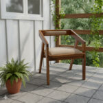 Solid Suar wood armchair with beige upholstered seat and backrest on a covered terrace