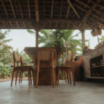 Low-angle view of Artisan Suar wood dining table with teak chairs and woven rattan backrests