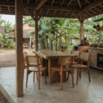 Artisan Suar wood dining table and teak rattan chairs arranged in a natural rustic dining space