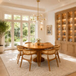 Bravelle solid teak round dining table with woven cane chairs in a modern dining room