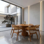 Solid teak round dining table with woven cane chairs in a bright elegant dining room