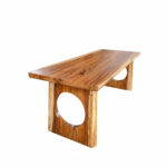 Solid Suar wood dining table with sculptural circular cut-out legs, three-quarter view