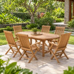 Teak folding garden chairs arranged around an oval teak outdoor dining table in a garden setting