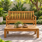 Dhifa teak garden bench placed on a green lawn surrounded by flowering plants
