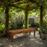 Solid teak garden bench with slatted seat in a landscaped garden