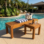 Teak slatted outdoor bench beside a swimming pool