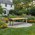 Nico Rect rectangular Suar wood dining table displayed on a garden patio surrounded by flowers and greenery