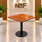 Niwara square teak wood cafe table with black metal pedestal base in a furniture showroom