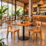 Niwara square teak wood cafe table with black metal pedestal base in a modern cafe