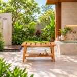 Teak spa bench with lower shelf in outdoor bathroom setting