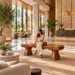 Terra suar wood bench with sculptural pedestal legs displayed in a luxury hotel lobby